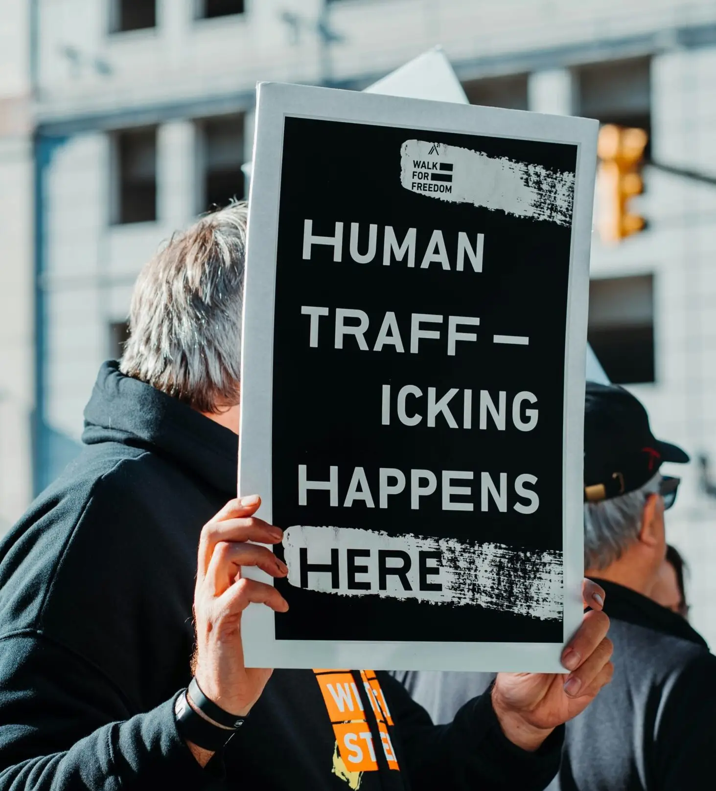 man in black jacket holding black and white quote board